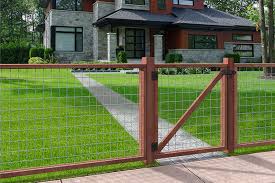 Dark wood fence with silver wire-mesh panels and a matching gate opening onto a lawn path toward a modern house